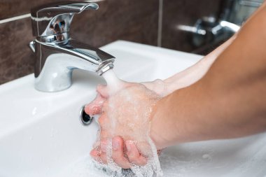 Hijyen konsepti. Musluğun altında sabunla ellerini yıkamak, suyla.