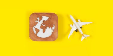 Uçak modeli, yüz maskesi ve sarı arka planda toprak modeli. Coronavirüs 'ün uçuş etkisi (COVID-19) kavramı.