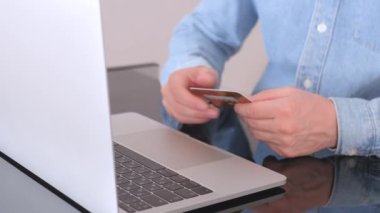 Elinde kredi kartı olan bir adamın erkek elleri bankaya çevrimiçi ödeme yapıyor. İnternet mağazasında satın almak için laptop teknolojisi kullanan adam. E Ticaret web sitesi ödemeleri konsepti. Görüntüyü kapat