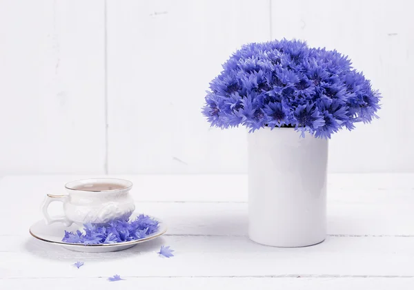 Cornflowers and tea in ceramic cup — Stock Photo, Image
