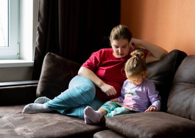 Anne ve kızı evde tablet kullanıyor. Annelik, bir çocukla vakit geçirmek. Ebeveyn sevgisi.