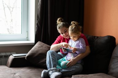 Anne ve kızı evde tablet kullanıyor. Annelik, bir çocukla vakit geçirmek. Ebeveyn sevgisi.