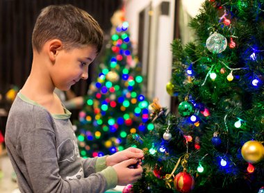 Noel ağacını oyuncaklar ve toplarla süsleyen bir çocuk.. 