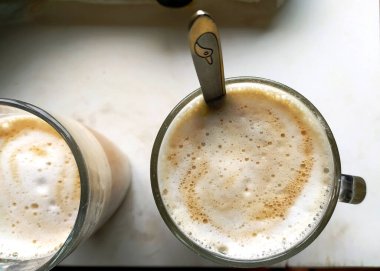 Köpüklü bir kahvenin tepetaklak manzarası. Temiz bir cam bardakta, kaşıkla. Sıcaklığı, rahatlığı ve basit zevkleri çağrıştırıyor. Sabahları, molaları ya da rahat anları resmetmek için birebirdir..