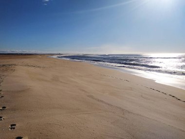 Saf sükuneti, el değmemiş bir kumsalın geniş açılı görüntüsünü ve parlak mavi bir gökyüzünün altında okyanus dalgalarını deneyin. Seyahat, sağlık ve doğa temalı projeler için mükemmel..
