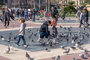 Barcelona, İspanya - 24 Şubat 2020: Yayalar güneşli bir kış öğleden sonra Plaza de Catalunya 'da güvercinleri besliyor