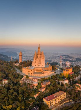 Aerial drone view of Basilica Sacred Heart on Mount Tibidabo near Barcelona during sunset golden hour clipart