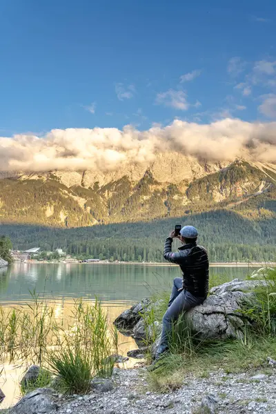 Turist, Eibsee Gölü 'nün kıyısında Alpengspitze' den önce yoğun sisin fotoğrafını çekiyor. — Stok fotoğraf