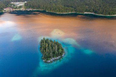 Zugspitze 'nin Almanya' daki altın saatinde Eibsee Gölü 'ndeki ağaçların insansız hava aracı görüntüleri.