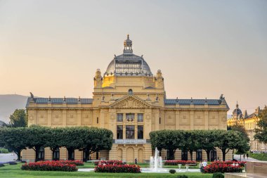 Zagreb, Hırvatistan - 10 Ağustos 2020: Kral Tomislav parkında gün batımında Sanat Pavyonu 'nun sarı cephesi