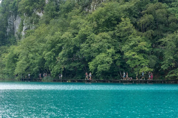 Plitvice, Croatie - 11 août 2020 : Les touristes marchent au bord d'un lac couleur aqua — Photo