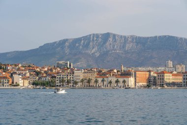 Sürat teknesi, sabahın erken saatlerinde Coratia 'daki Morso Dağı manzaralı eski kasaba Riva' sına doğru gidiyor.