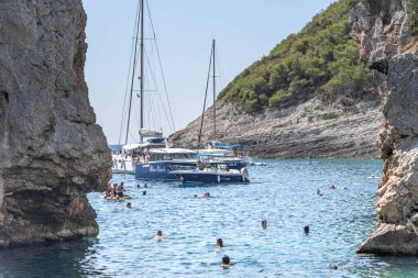 Vis, Hırvatistan - 17 Ağustos 2020: İnsanlar yazın korunaklı Stiniva plaj koyunda yüzüyor