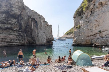 Vis, Hırvatistan - 17 Ağustos 2020: Korunaklı körfez Stiniva plajında güneşlenen turistler