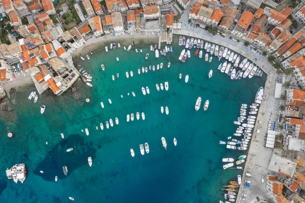 Aerial overhead drone shot of Komiza town port with boats in early morning on Vis Island in Croatia summer