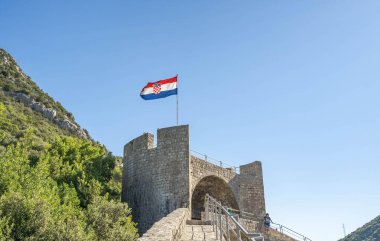 Ston, Hırvatistan - 20 Ağustos 2020: Yazın Ston Duvarında dalgalanan ulusal bayrak ile kale