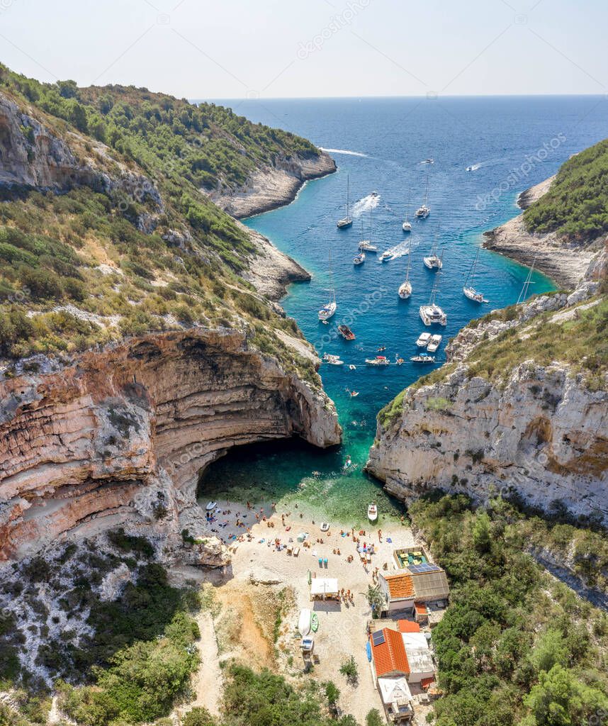 Aerial drone shot of tourists swim sunbath at Stiniva cove beach of Adriatic sea on Vis Island in Croatia summer