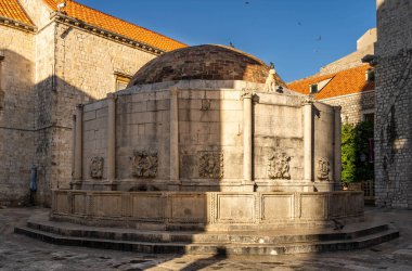 Dubrovnik, Hırvatistan - 22 Ağustos 2020: Büyük Onofrios Çeşmesi güneş doğarken eski kasaba sokaklarında oyulmuş maskelerle