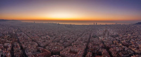 Aerial panorama drone shot of Barcelona with sunrise over sea horizon in Spain winter dawn