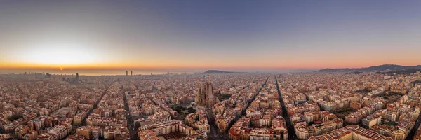 Panoramic aerial drone shot of Barcelona city skyline with church before sunrise in winter