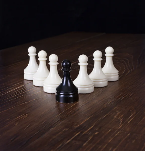 Black pawn in focus on a background white pawns. — Stock Photo, Image
