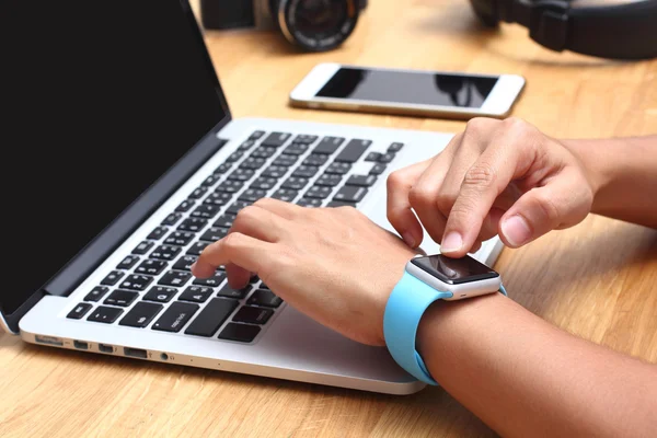 Hands of woman wearing touch screen smartwatch on the keyboard o — Stock Photo, Image