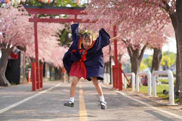 快乐的亚洲小女孩毕业了 在樱花树的背景下 — 图库照片