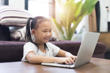 Mutlu Asyalı küçük kız öğrenci evde sanal internet öğreniyor.