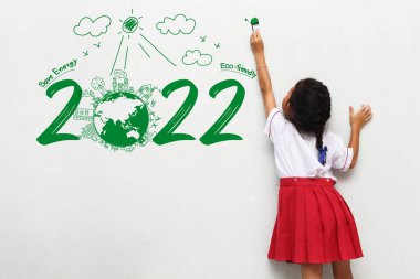 Asyalı küçük kız elinde boya fırçasıyla yaratıcı bir çevre ve çevre dostu tablolar yapıyor, 2022 yılının enerjisini boşa harcamasın.
