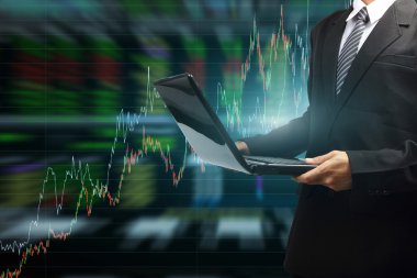 hisse senedi grafiği ile modern bir dizüstü bilgisayarda yazarak iş adamı
