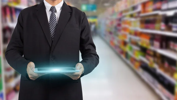 Hands holding and touching on tablet pc in supermarket in blurry — Stock Photo, Image