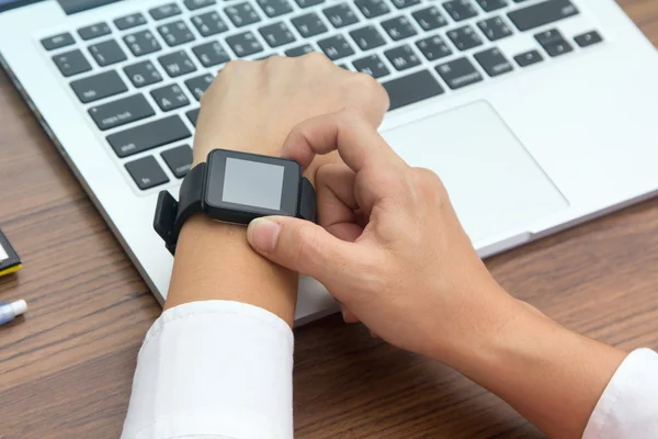 Close up tiro de mão com smartwatch no computador portátil — Fotografia de Stock