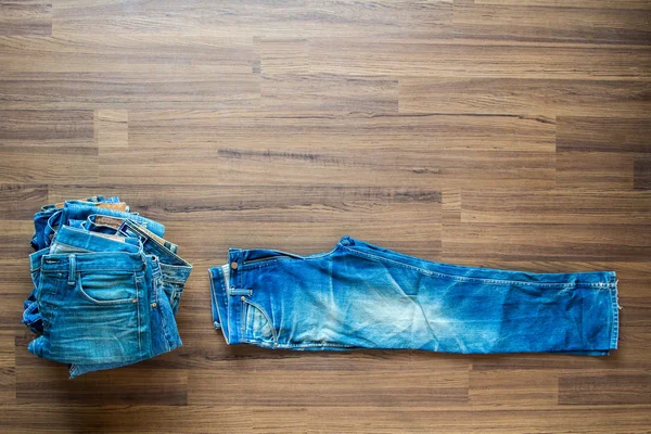 Jeans apilados sobre un fondo de madera — Foto de Stock