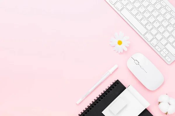 Minimal Office desk table with Keyboard computer, mouse, white pen, cotton flowers, eraser on a pink pastel table with copy space for input your text, pink color workplace composition, flat lay, top view