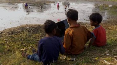 Katni İlçesi, Madhya Pradesh, Hindistan - 4 Ocak 2021: Üç fakir çocuk birlikte dizüstü bilgisayar eğitimi öğreniyor kırsal alanda çevre hakkında video 4k.