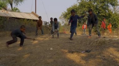 Katni İlçesi, Madhya Pradesh, Hindistan - 04 Ocak 2021: Köyün kırsal kesiminde sopayla plastik top oynayan fakir çocuklar grubu.