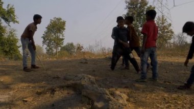 Katni Bölgesi, Madhya Pradesh, Hindistan - 04 Ocak 2021: Köyün kırsal kesiminde sopayla kriket oynayan bir grup Asyalı fakir çocuk.