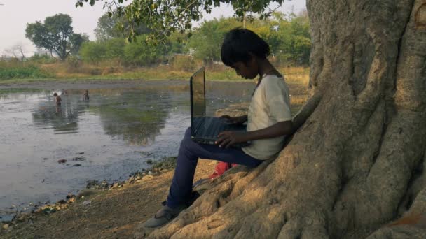 印度中央邦Katni区 2021年1月4日 一名亚裔村贫穷女童在湖景视频视频画面上学习村庄背景的笔记本电脑 — 图库视频影像