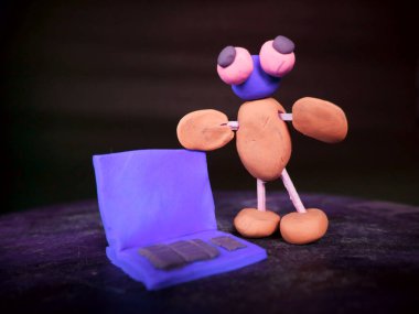 Çizgi filmdeki kil adam dizüstü bilgisayarla mavi arka planda duruyor.