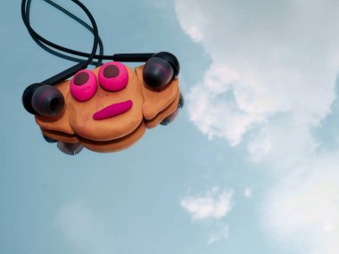 Cam gökyüzü yansıma yüzeyinde kilden yapılmış karikatür yüzüyle baş telefonu sunuldu..