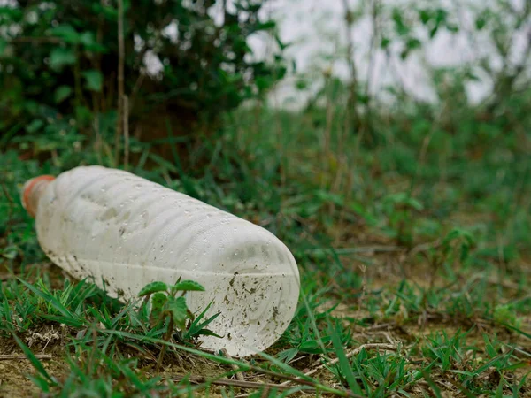 Yeşil Çimen Tarlasında Sunulan Kullanılmış Şişesi Plastik Kirliliği Kavramı — Stok fotoğraf
