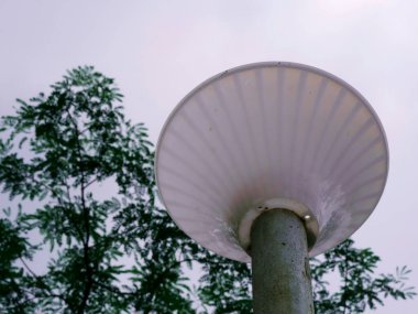 Beyaz renkli hafif yapı gökyüzü arka planında ayakta duran metal direkle sunuluyor.