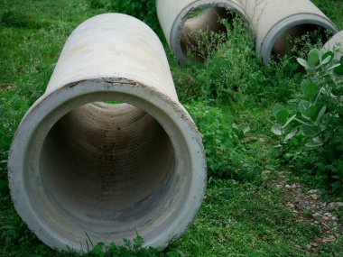 Yeşil çimen tarlasında sunulan beton boru, endüstriyel kavram.