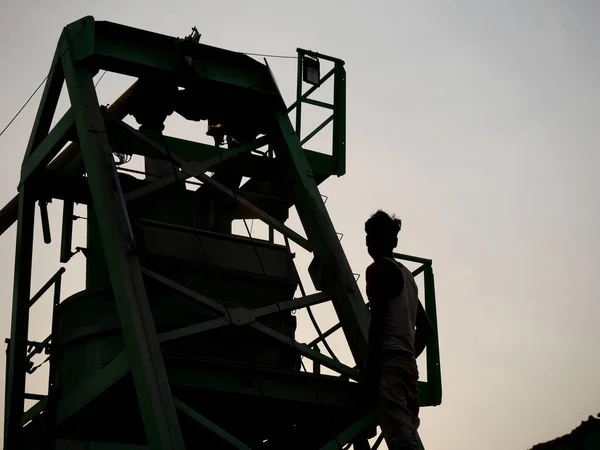 Asian labor working at concrete mixer machine presenting around sky silhouette industrial background.