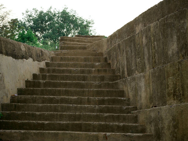 Historical concrete stairs down to up view at forest area natural sky background.