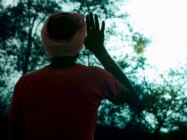 Köylü adam ağaç arka planındaki güneş ışığından yararlanıyor..