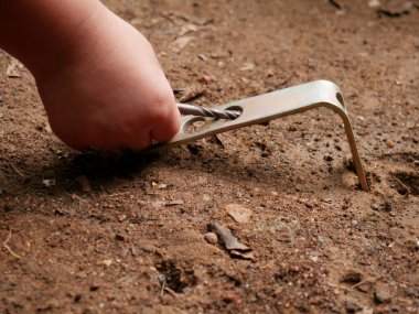 Erkek çocuk elinde vida aletleri ile toprağı kazıyor..