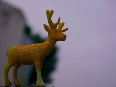 Geyik oyuncağı doğal yeşil yapraklarla sunuluyor gökyüzü arkaplanıyla, çocuklar nesne doğal görüntüsüyle oynuyor.