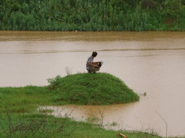 Hintli köylü nehir kıyısında dizüstü bilgisayarda çalışıyor. Doğal çevre geçmişi..