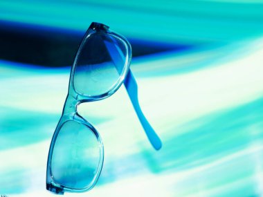 Mavimsi güneş gözlükleri ışık efektiyle sunuluyor. Arkaplan parlıyor. Ticari ürün sunumu görüntüsü..